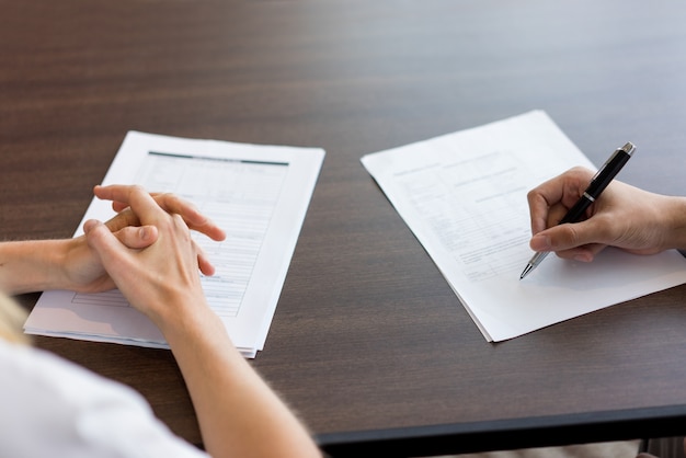 Female hand filling in questionnaire for male candidate. 