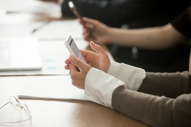 Free photo female hands holding mobile phone at office meeting, closeup view