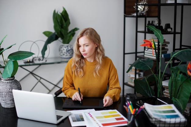 Foto gratuita designer di logo femminile che lavora sul suo tablet collegato a un laptop