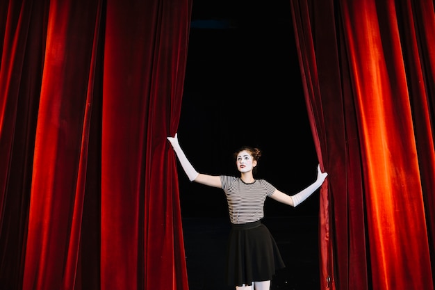 Free photo female mime artist holding red curtain