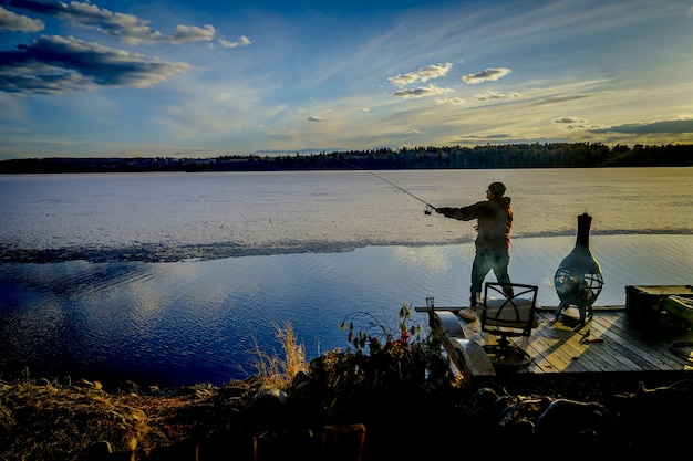 Free photo fisherman on a pier catching fish during a sunny beautiful day