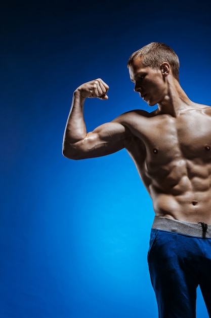 Free Photo fit young man with beautiful torso on blue wall