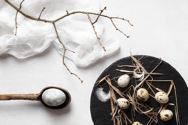 Free Photo flat lay of easter eggs on slate with wooden spoon and twig