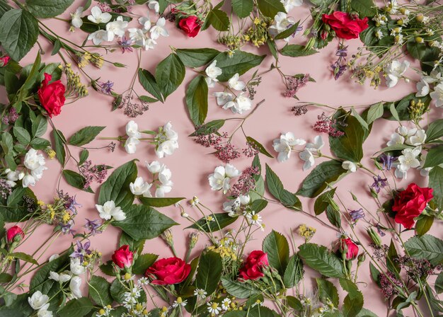 Floral arrangement with different fresh flowers, leaves and twigs on a pink surface