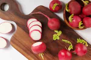 Free photo fresh red radish on cutting board. set of fresh whole small garden radish isolated on white surface. top view. flat lay. freshly picked from home growth organic garden. food concept.