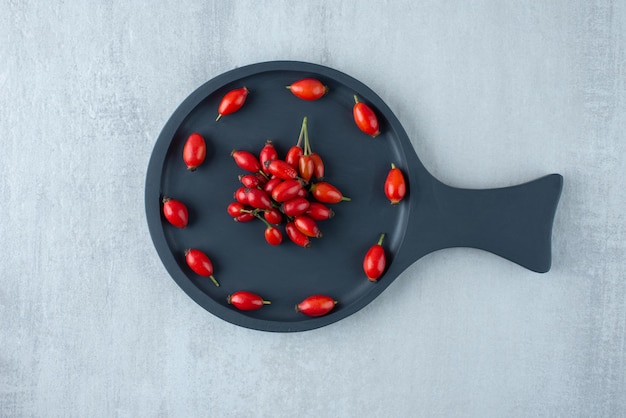 Free photo freshly picked rosehips on black board.