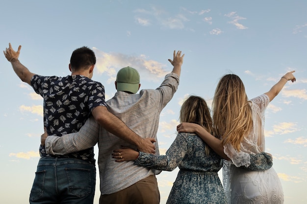 Free photo friends embracing at the beach looking at the sky