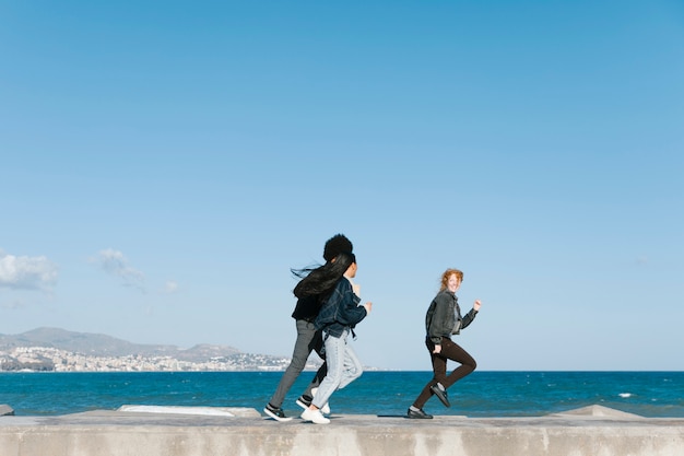 Free photo friends running in front of sea