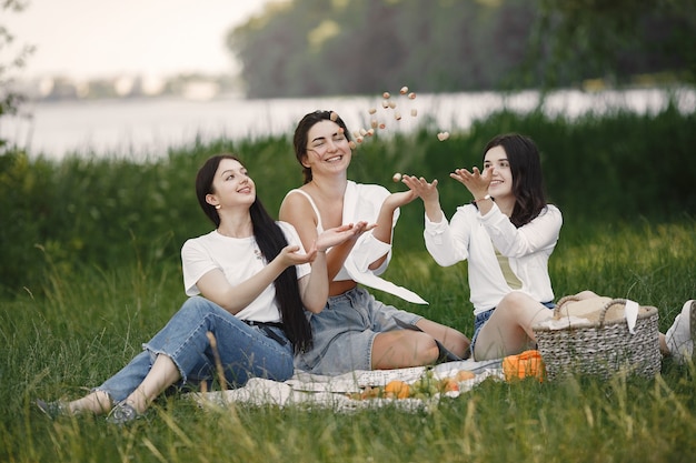 Бесплатное фото Друзья сидят на траве. девочки на одеяле. женщина в белой рубашке.
