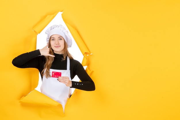 Front view female cook holding red bank card on yellow job photo emotion food kitchen color money cuisine