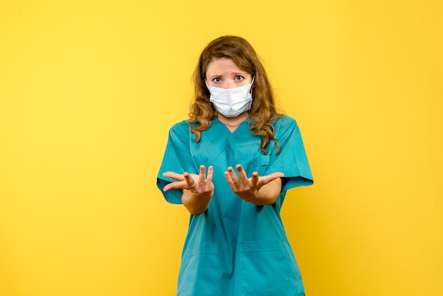 Free photo front view female doctor in mask on yellow space