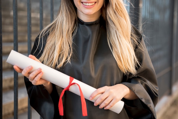 Foto gratuita ragazza di vista frontale che sorride tenendo il suo certificato