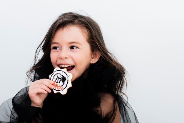 Free photo front view happy little girl eating a cookie