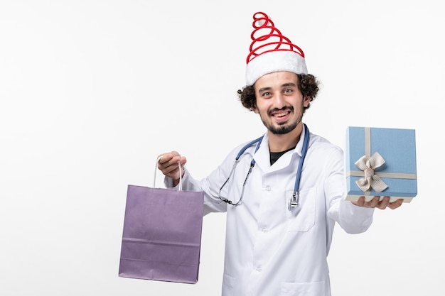 Free photo front view of male doctor holding presents on white wall