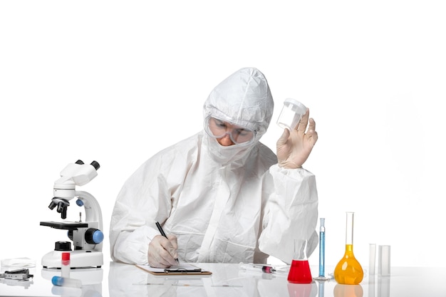 Free photo front view male doctor in protective suit holding empty flask and writing on white space