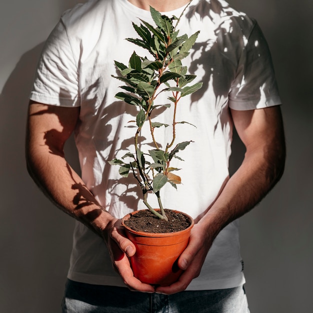 Free photo front view of man holding pot with plant