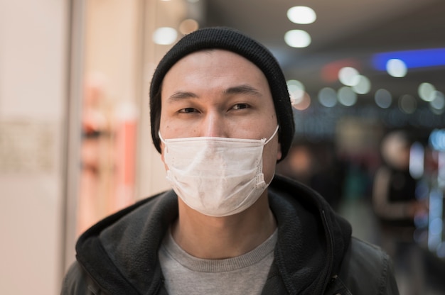 Free photo front view of man posing while wearing medical mask