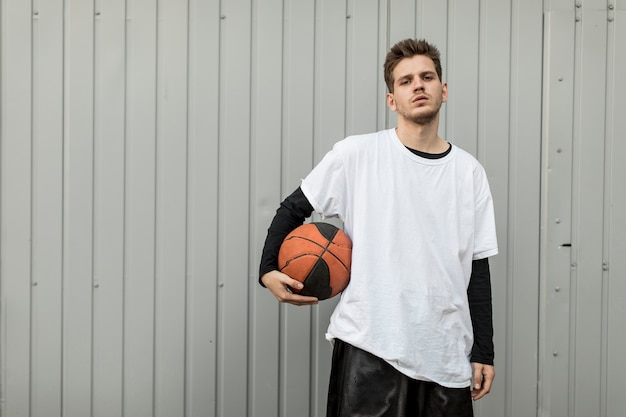 Foto gratuita uomo di vista frontale che posa con una pallacanestro