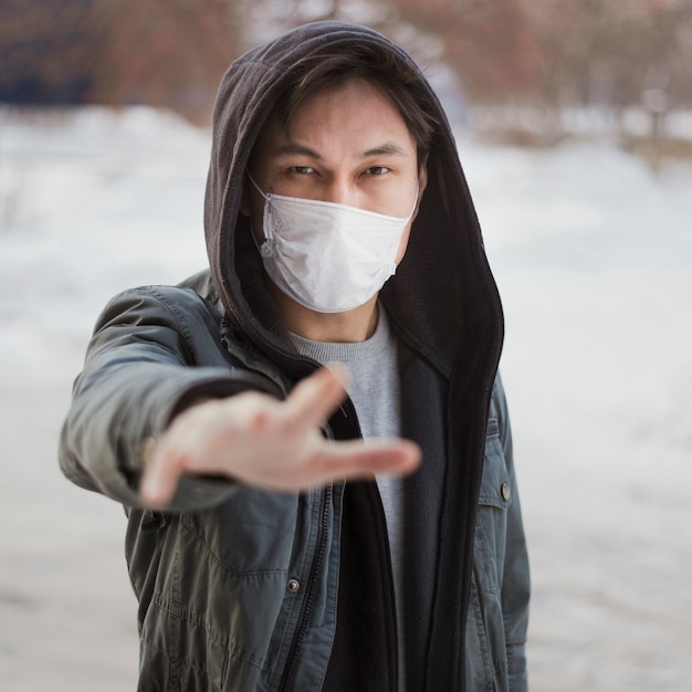 Free photo front view of man reaching for someone while wearing a medical mask