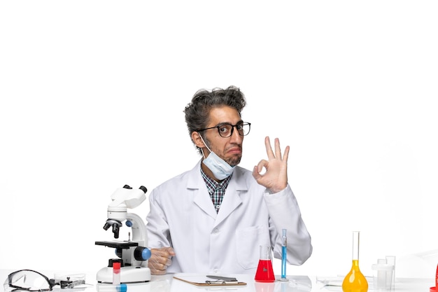 Free photo front view middle-aged scientist in special suit sitting around table with solutions