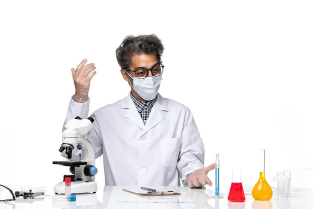 Free photo front view middle-aged scientist in special suit sitting and writing notes