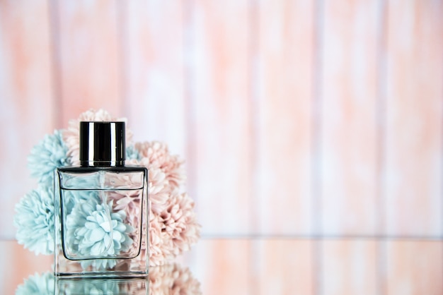 Free photo front view perfume bottle flowers on beige blurred background free space