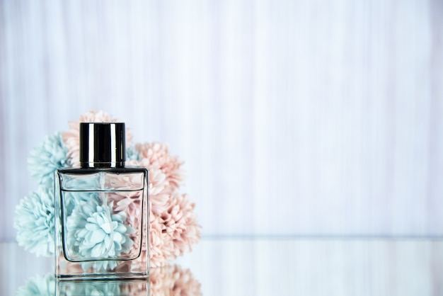 Free photo front view perfume bottle and flowers on light background