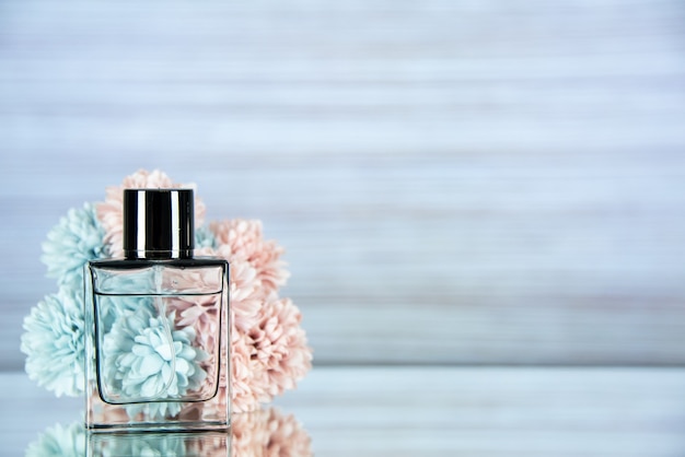 Free photo front view perfume bottle flowers on light grey background with free space