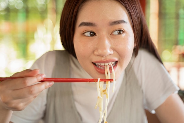 Free Photo front view smiley woman eating noodles