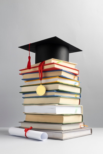 Free photo front view of stacked books, a graduation cap and a diploma for education day