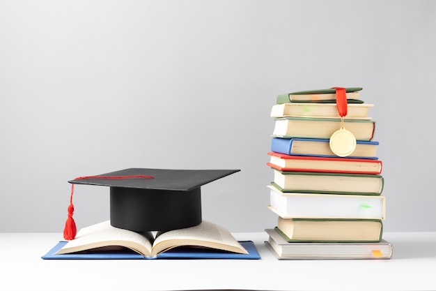 Free photo front view of stacked books, a graduation cap and an open book for education day