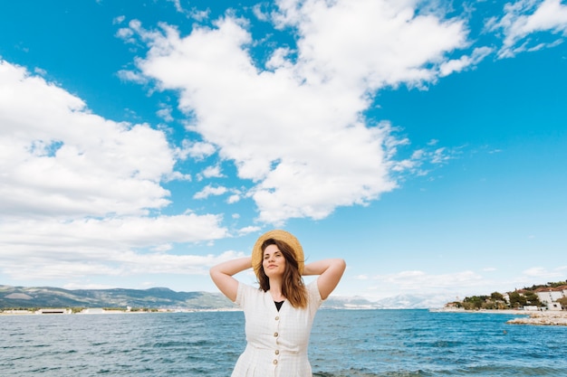 Free photo front view of woman posing at the ocean with clouds in the sky