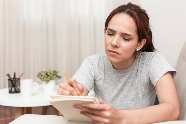 Front view of woman writing something down on notebook