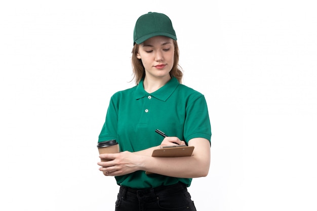 Free photo a front view young female courier in green uniform smiling holding notepad and coffee cup