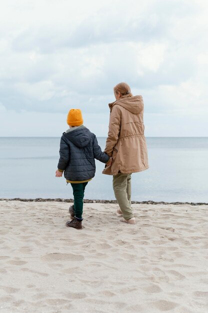 Full shot kid and woman holding hands