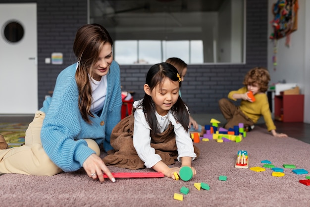 Free Photo full shot smiley teacher helping girl learn