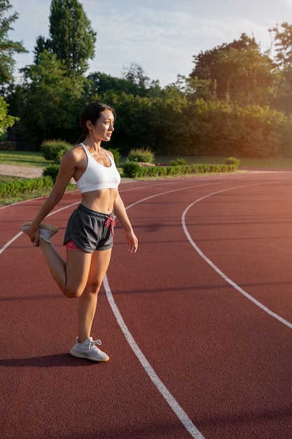 Free photo full shot woman stretching on running track