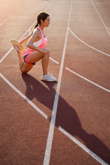 Free photo full shot woman stretching on running track