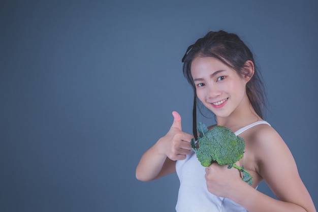 Free photo girl holds the vegetables on a gray background.