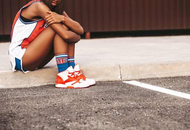 Free photo girl in red basketball sports clothes sitting on asphalt