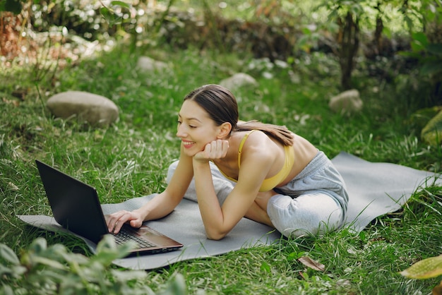 Free photo girl sitting in a summer park and holding a laptop in her hands