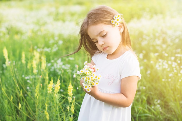 Free photo girl standing in the field looking at white flowers