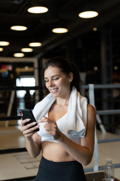 Free photo girl texting while taking a break in a gym. reads a message