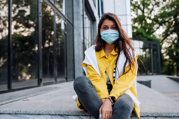 Free photo girl wearing mask posing on street. fashion during quarantine of coronavirus outbreak.