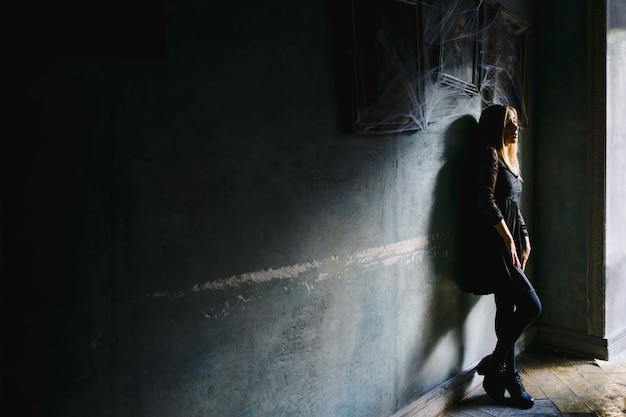 A girl with a dreamy view leans to a wall in a cafe