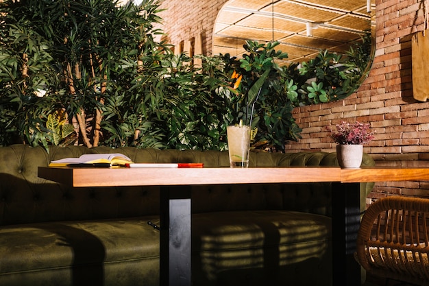 Free photo glass of cocktail; book; cellphone and digital tablet on wooden table in the restaurant