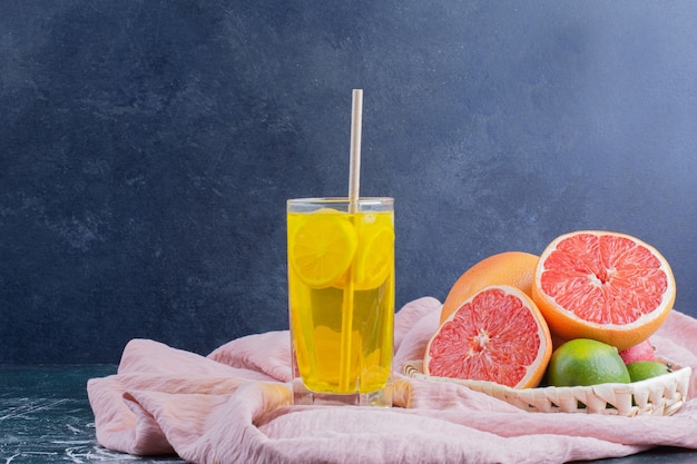 Foto gratuita un bicchiere di limonata con fette di limone e pompelmi sulla superficie in marmo.