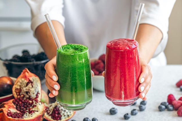 Free photo a glass of red and green smoothies in female hands closeup