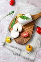 Free photo goat cheese slices on wooden board with ruccola,cherry tomatoes. ready to eat.