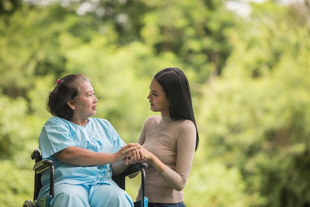 Granddaughter talking with her grandmother sitting on wheelchair, cheerful concept, happy family